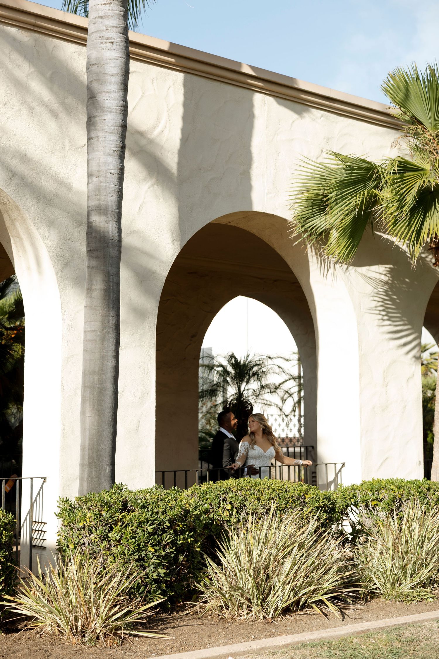 Palm trees and arched walkway with Mediterranean style architecture and landscaping.