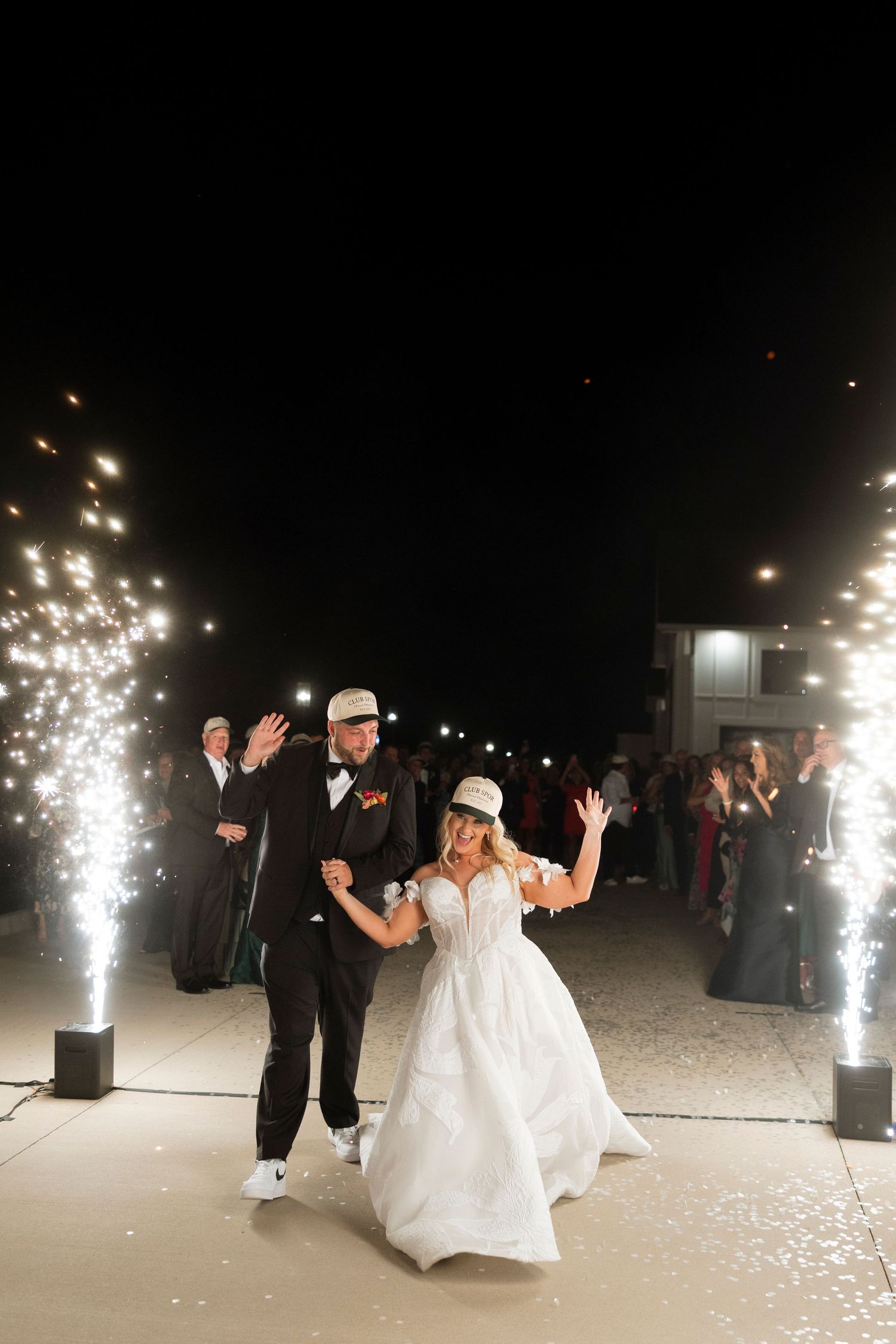 A couple celebrates on the dance floor at their wedding reception with sparklers illuminating the dark venue.