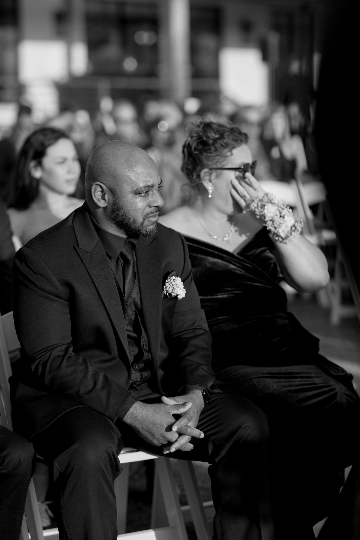 Black and white photo of wedding guests showing emotional reactions during ceremony.
