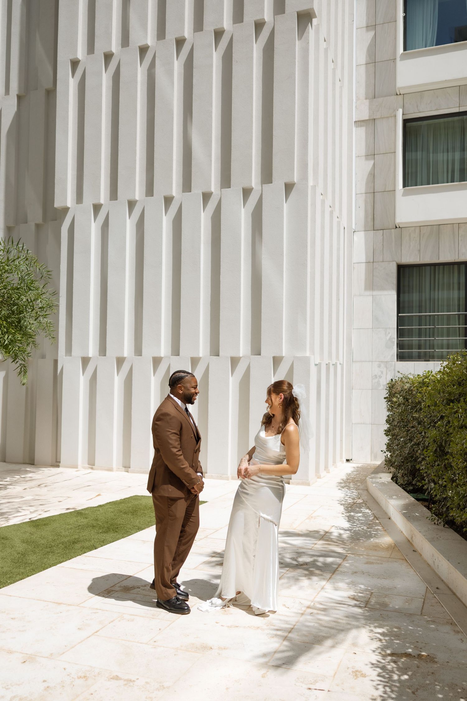 Architectural scene featuring white geometric building facade and manicured lawn.