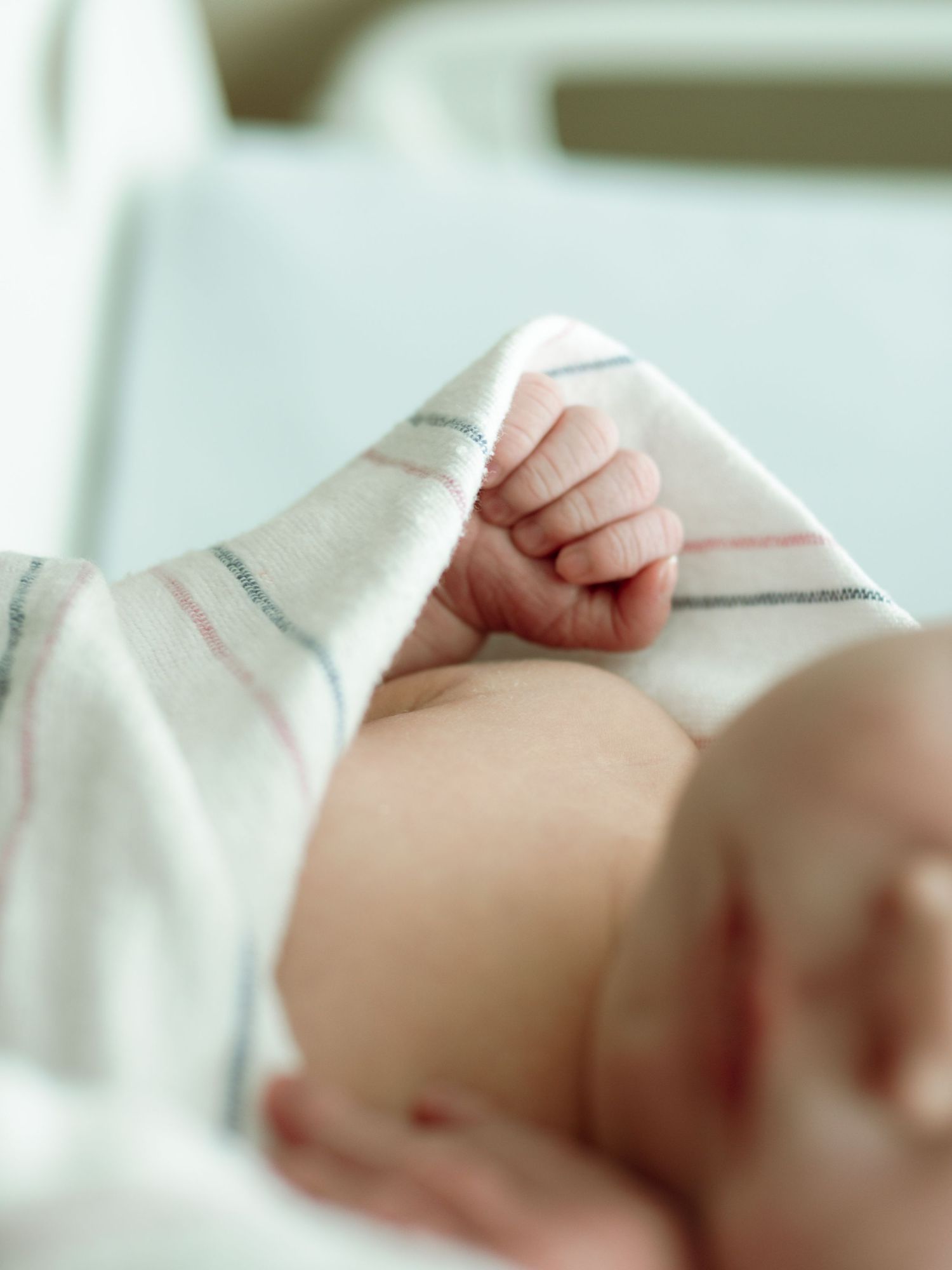 Close-up of a sleeping newborn baby wrapped in a striped hospital blanket.