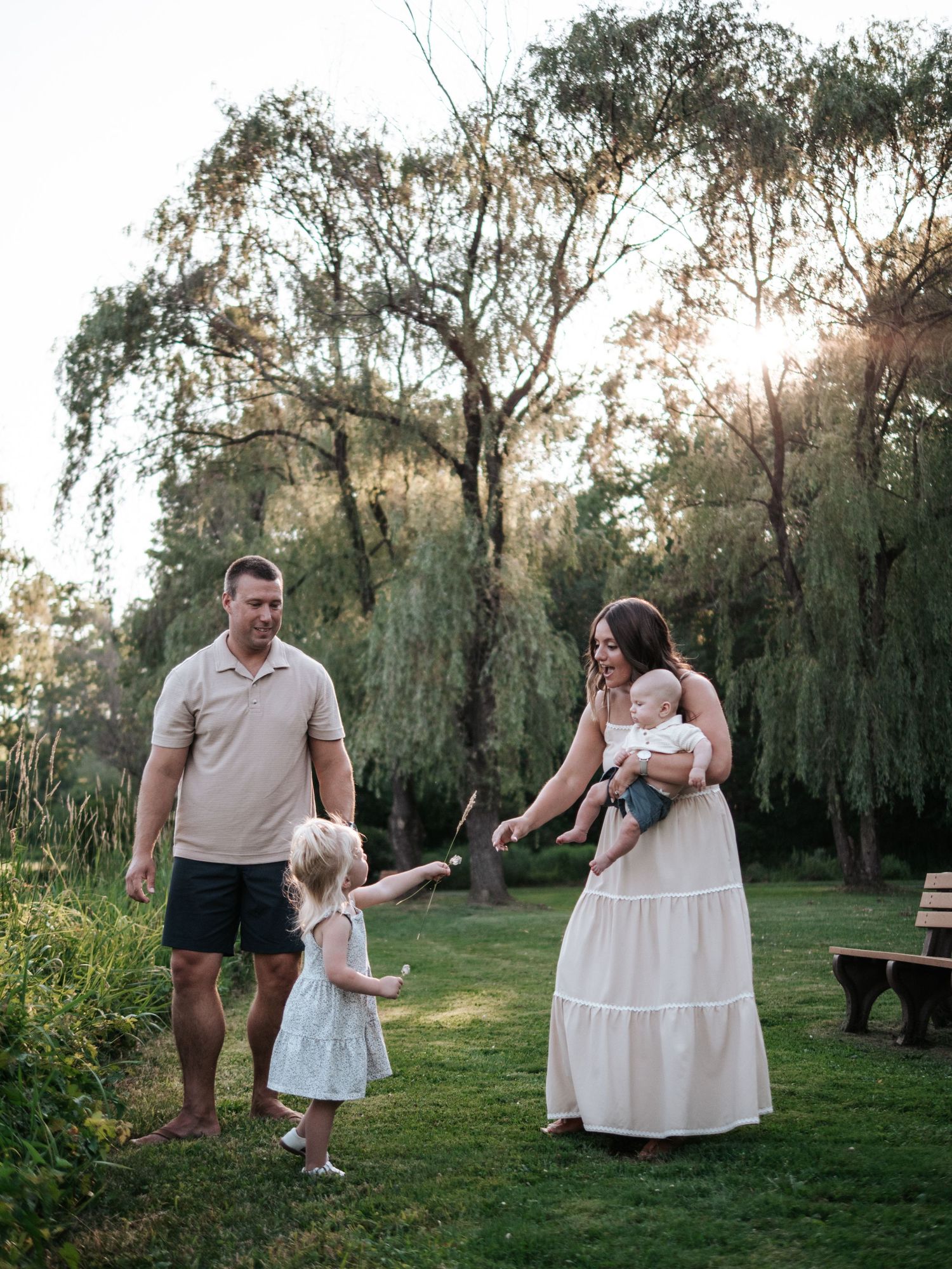 Family of four enjoying golden hour outdoors near a weeping willow tree.
