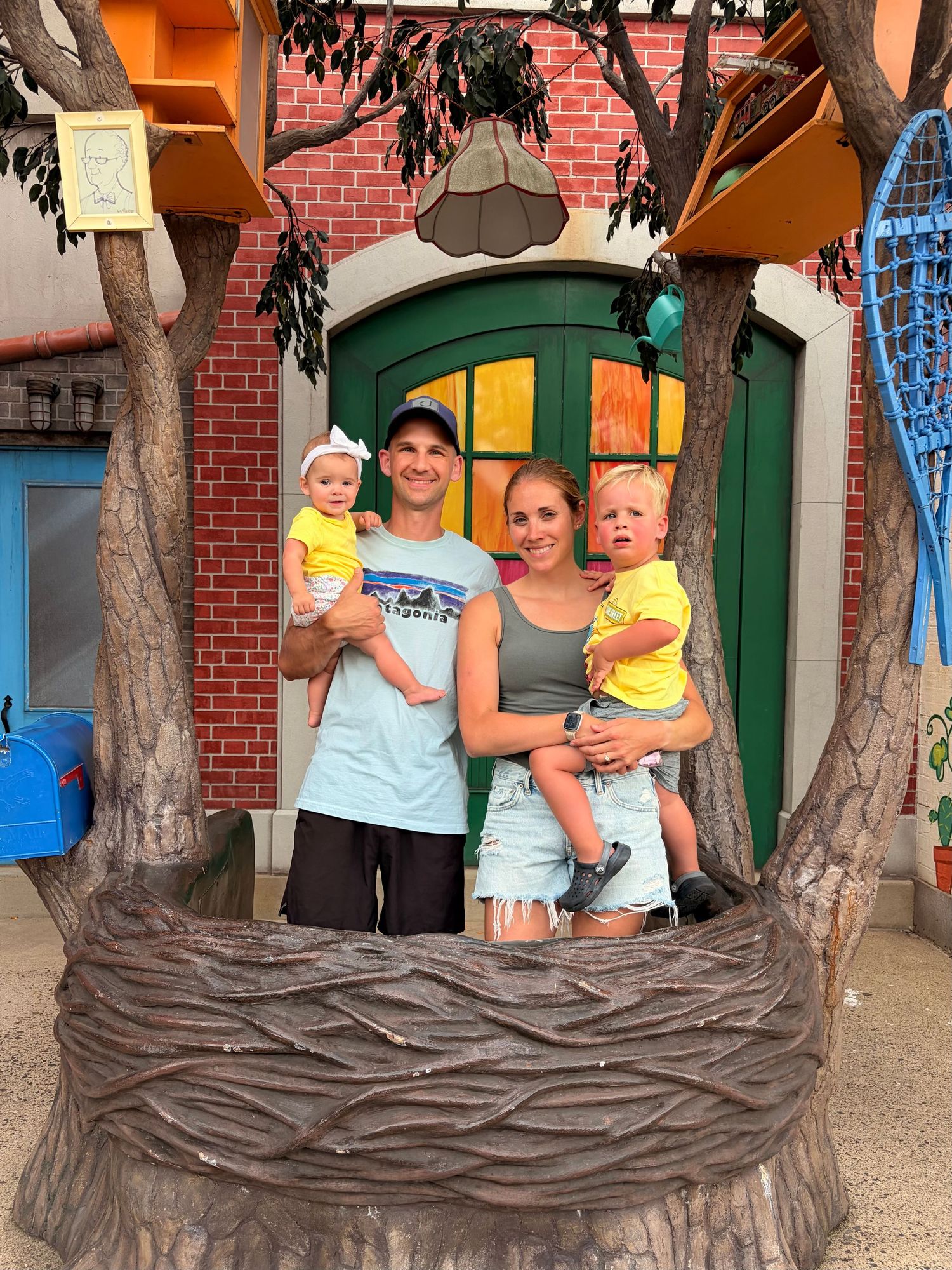 A family of four poses together in a colorful theme park attraction setting.