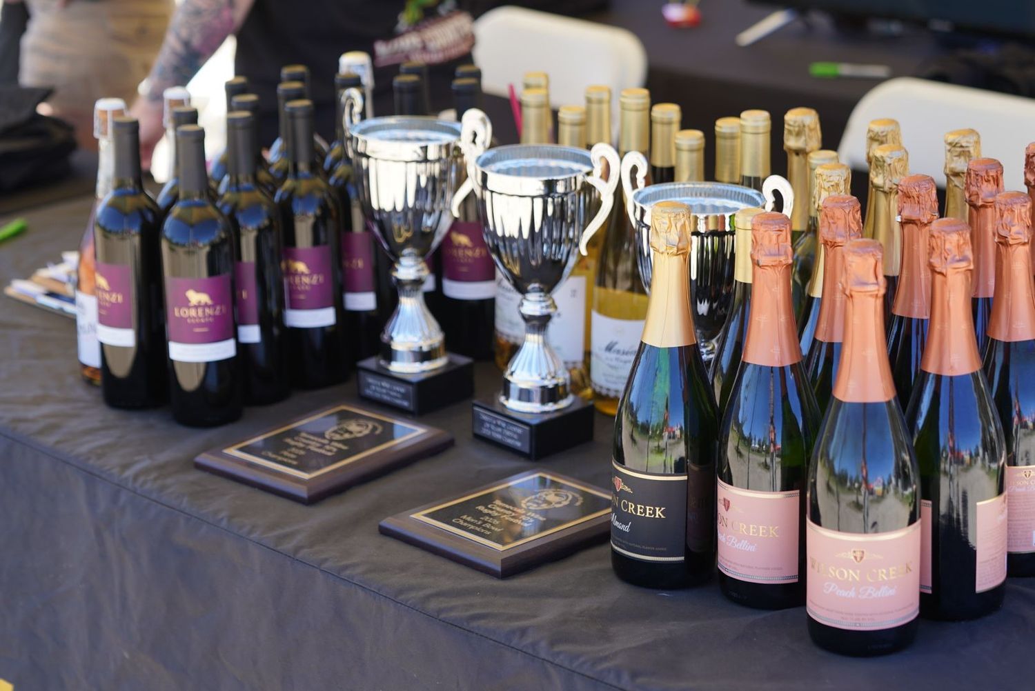 Wine bottles, trophies, and award plaques displayed on a table at a rugby competition awards ceremony in Temecula, CA's wine country.