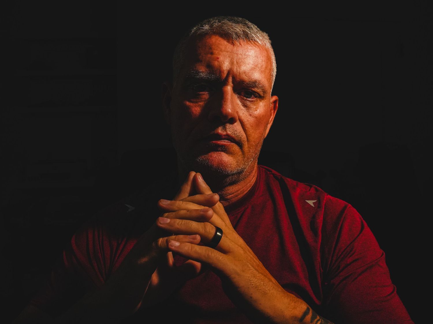Amarillo photographic artist Jon Chaffin in a dramatic low-key self-portrait with clasped hands and burgundy shirt