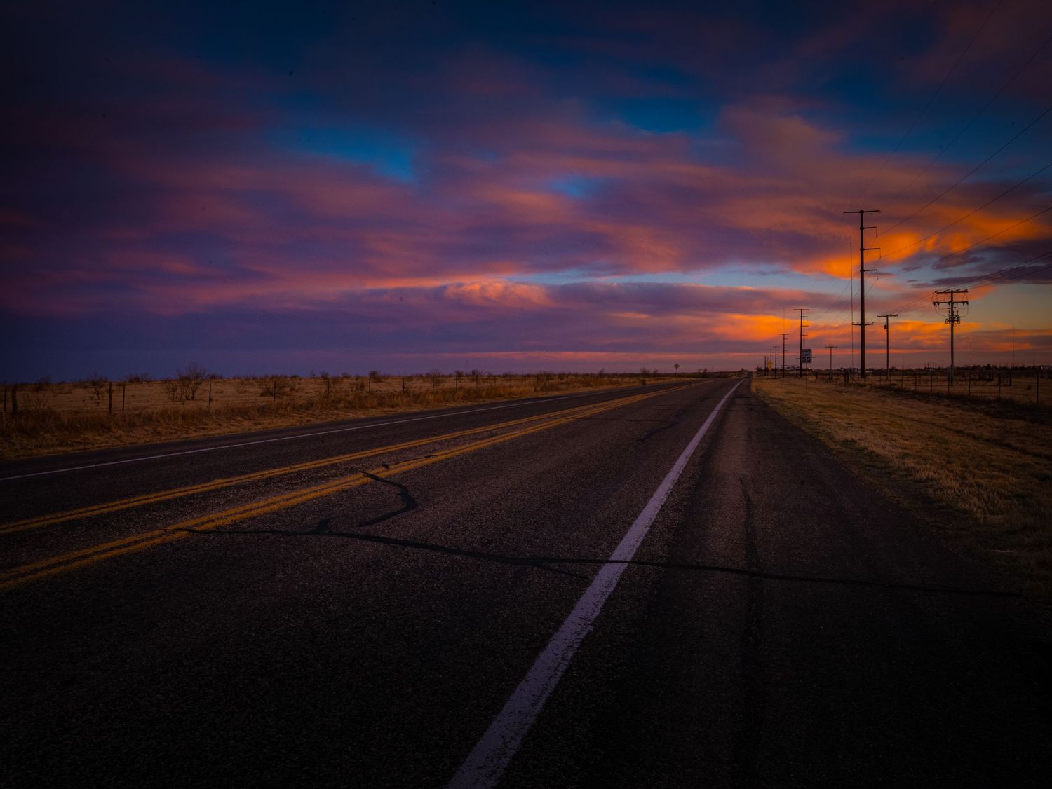 Texas Panhandle highway beneath dramatic purple and orange sunset clouds near Amarillo, Texas