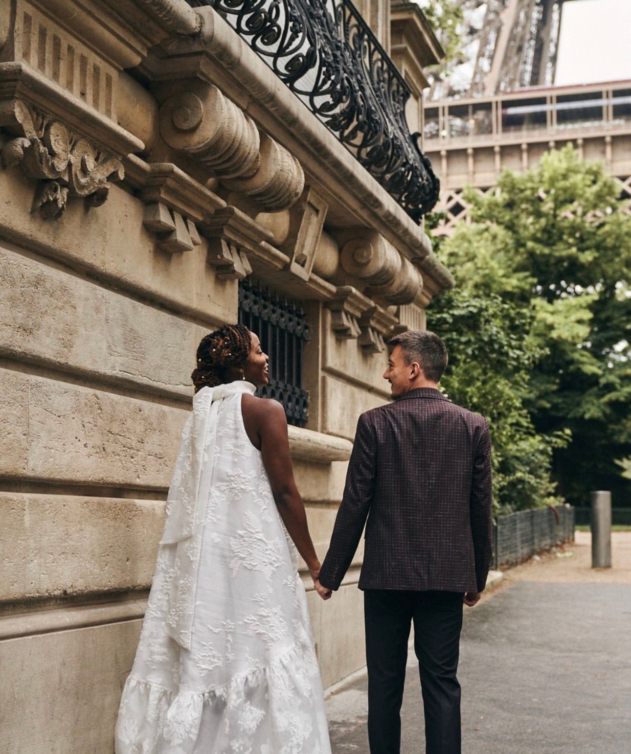 Mariés main dans la main dans une rue de Paris, robe à longue traîne et voile, photo de mariage