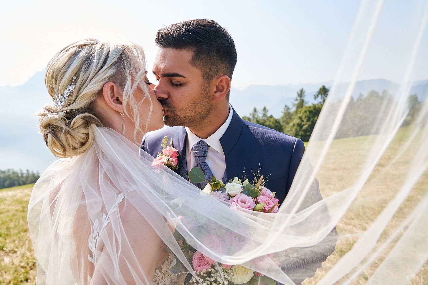 Mariés qui s'embrassent sous le voile de la mariée, portrait de couple en extérieur