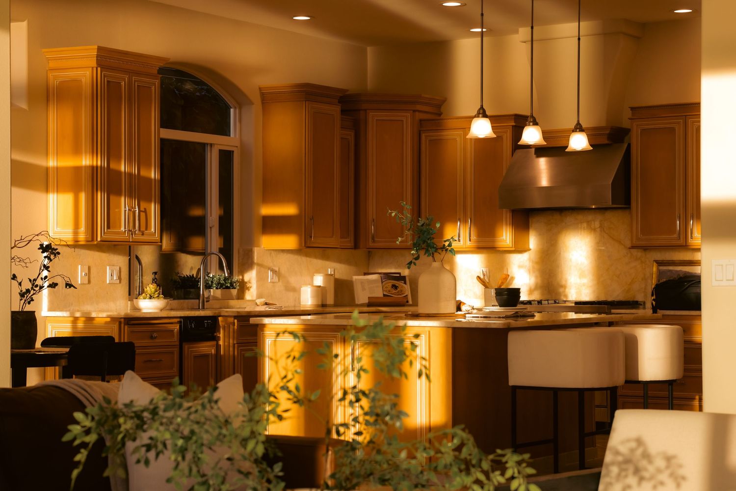 Warmly lit kitchen interior with wood cabinetry and pendant lighting.