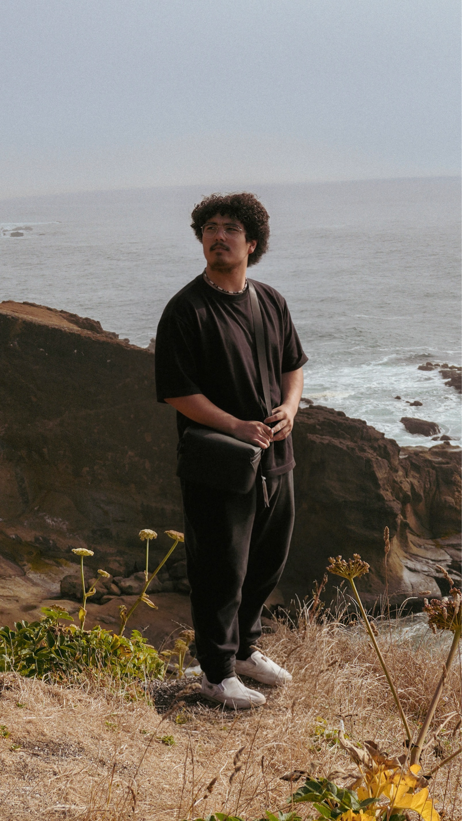 Portrait of a man standing on a rocky coastline overlooking the ocean.