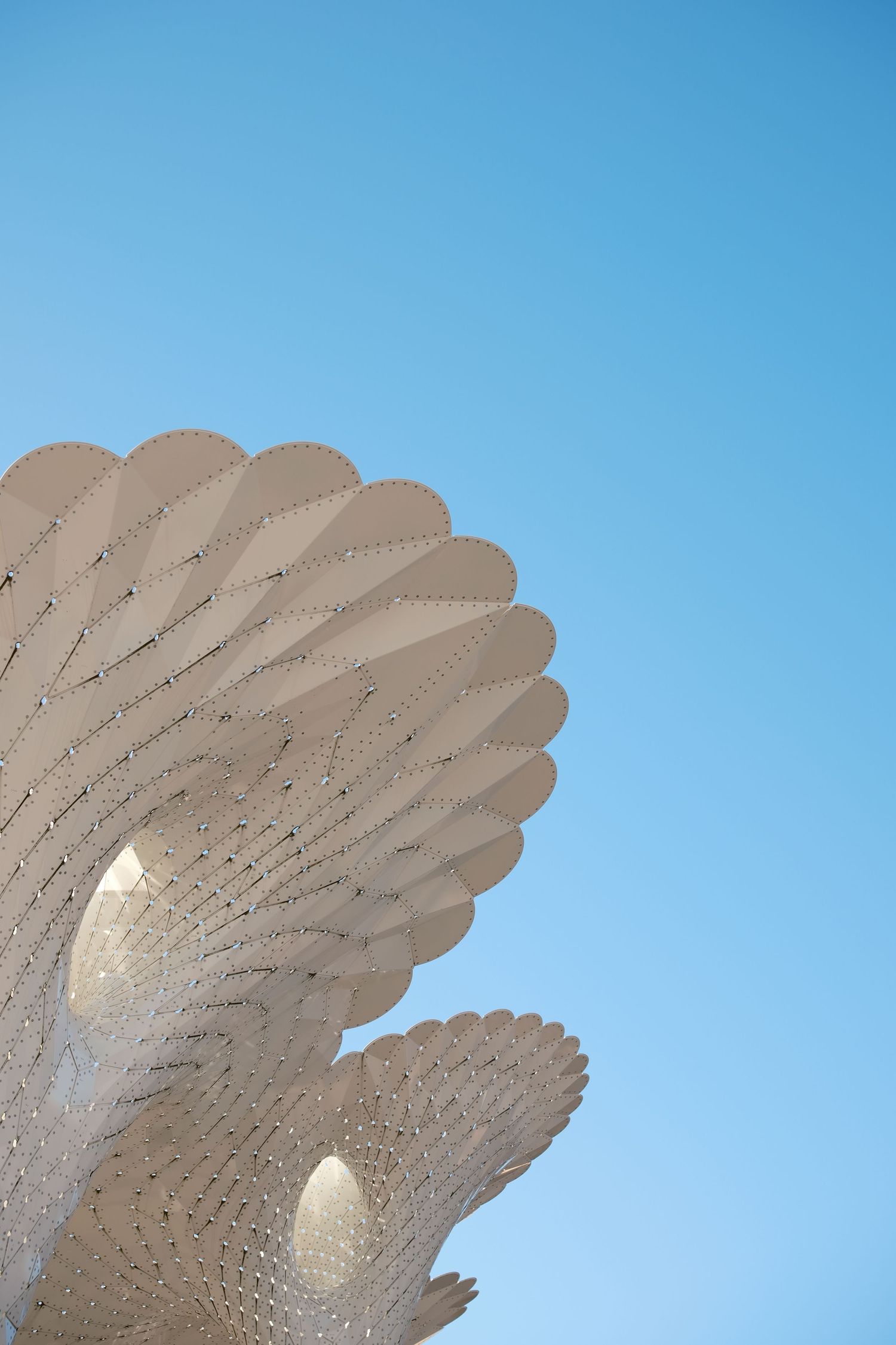 Abstract view of a white geometric architectural structure against a blue sky.