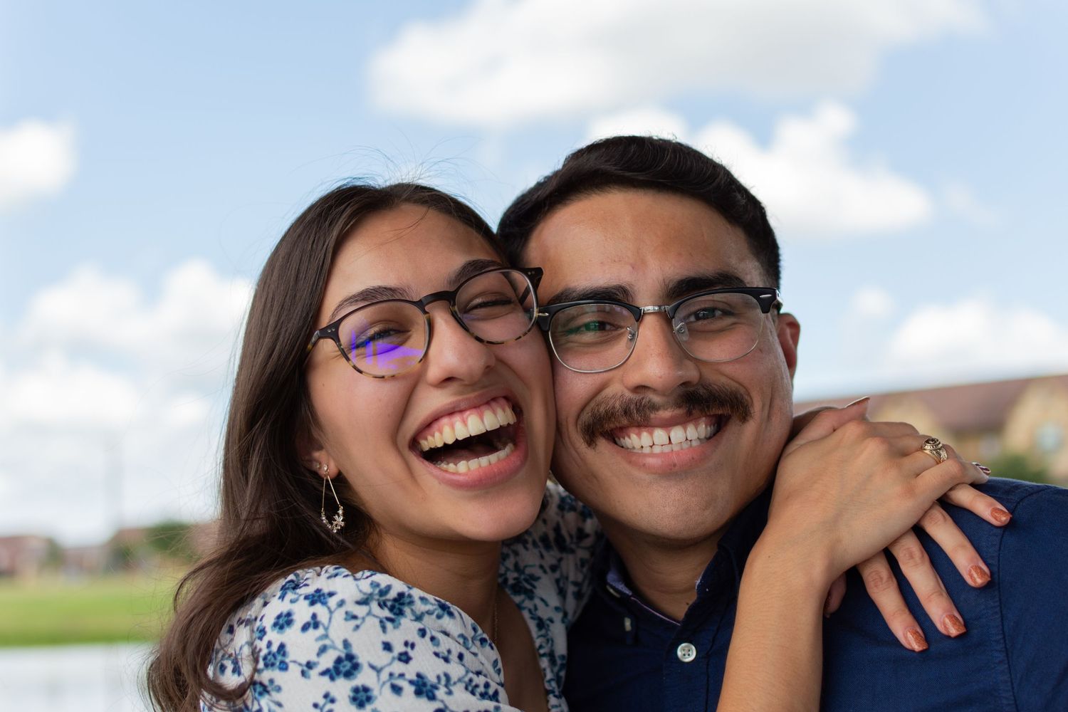 A newly engaged couple hug excitedly during a couples session on a sunny summer day in Texas.
