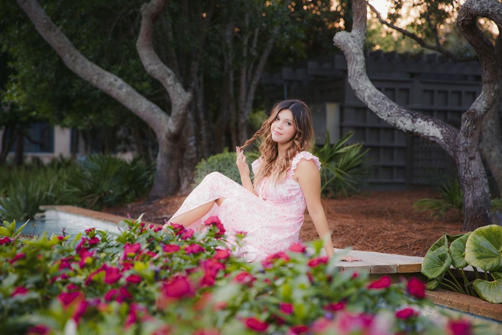 A dreamy outdoor portrait session in a garden with pink roses and sunlit trees creating a romantic atmosphere.
