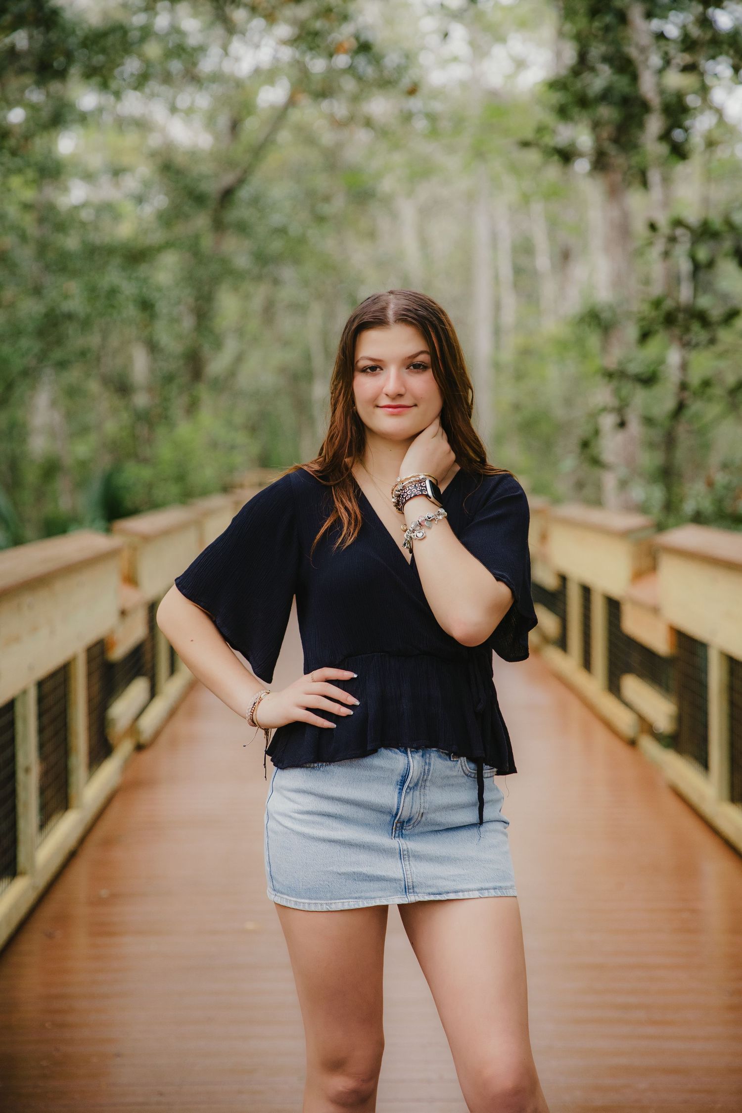 A casual portrait on a wooden boardwalk surrounded by lush greenery.