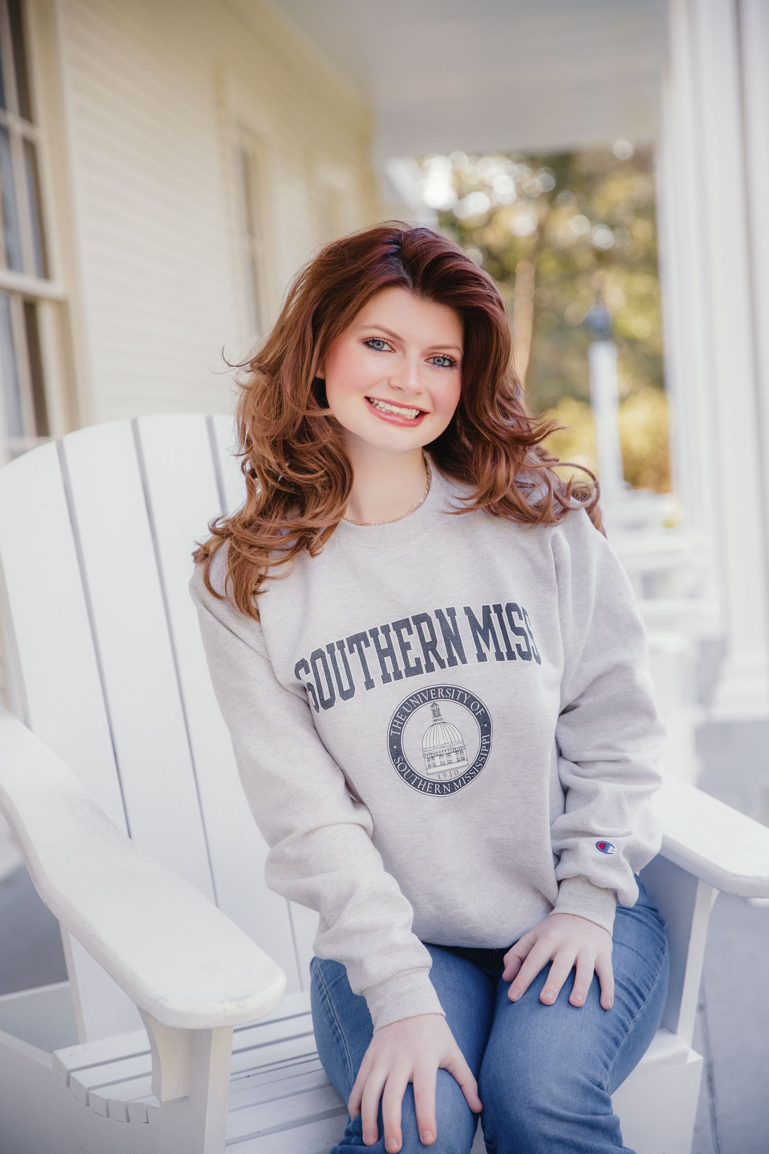 A relaxed portrait on a white porch wearing a Southern Miss university sweatshirt.