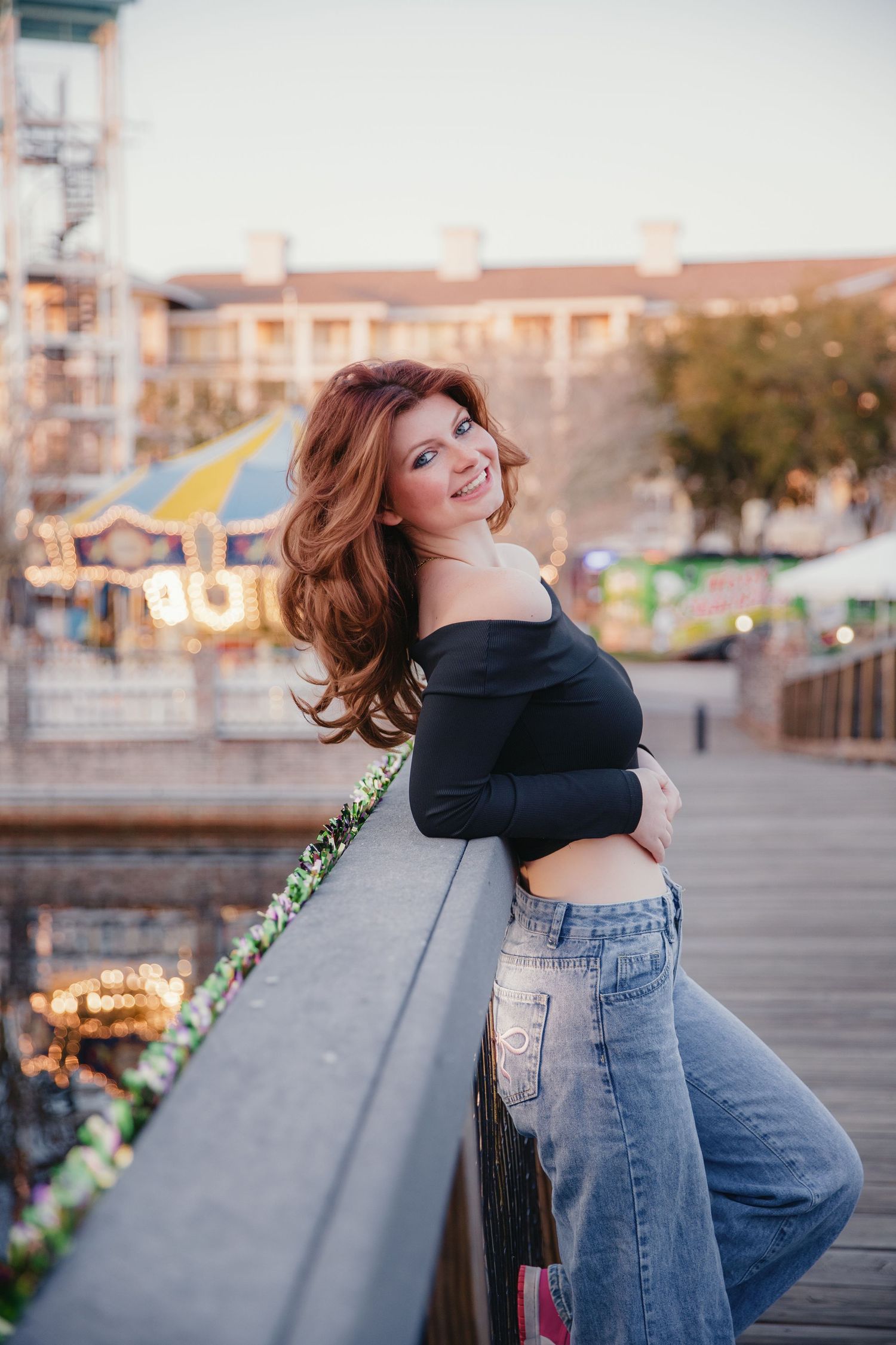 A stylish pose in crop top and jeans against an evening cityscape with twinkling lights.
