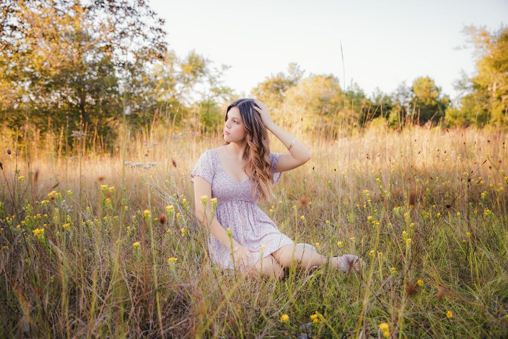 A dreamy autumn photoshoot in a golden field with tall grass and wildflowers at sunset.