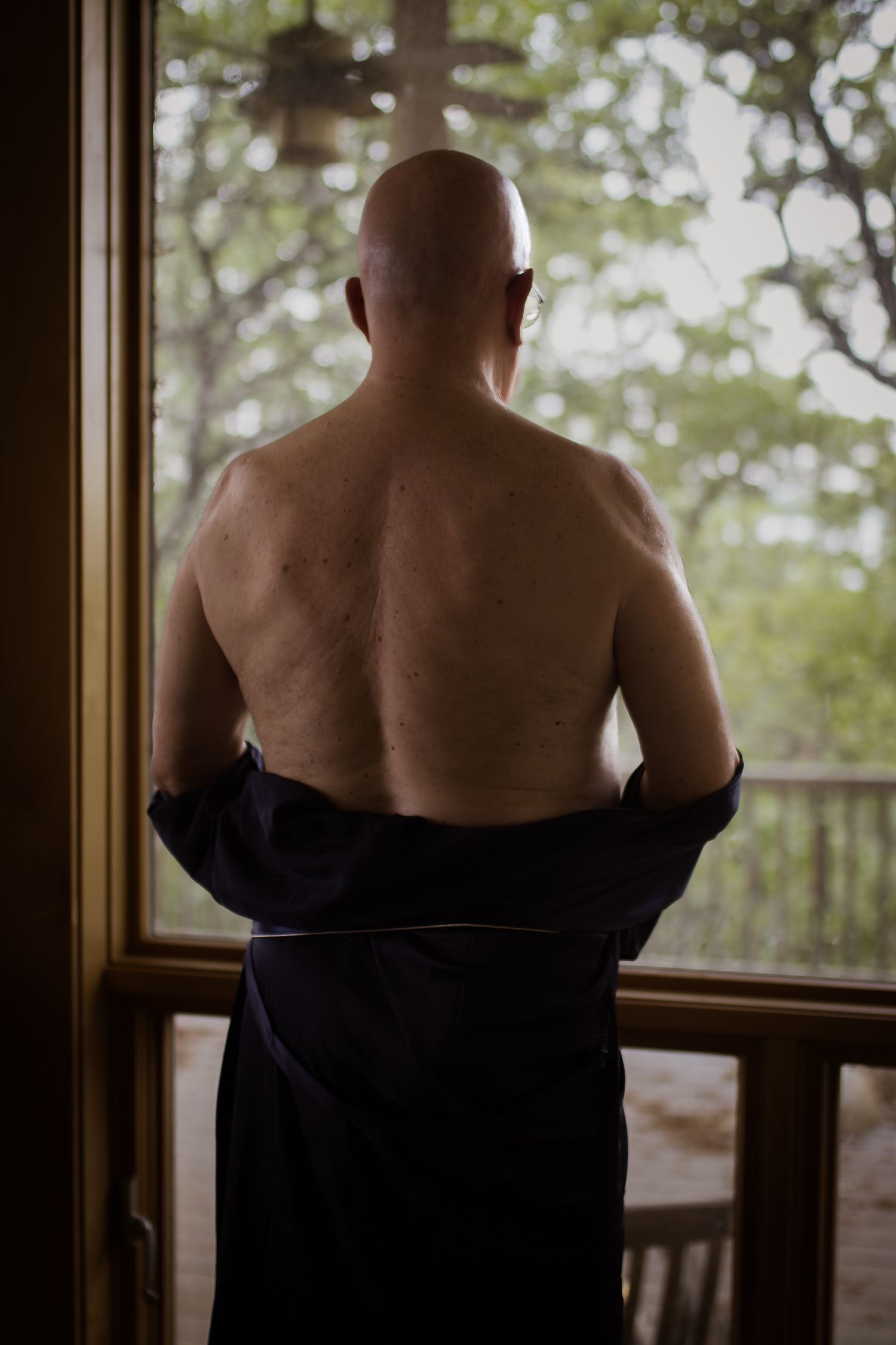 A Dallas man stares out his window during a male boudoir session with Lock and Key Photography based in north Fort Worth.