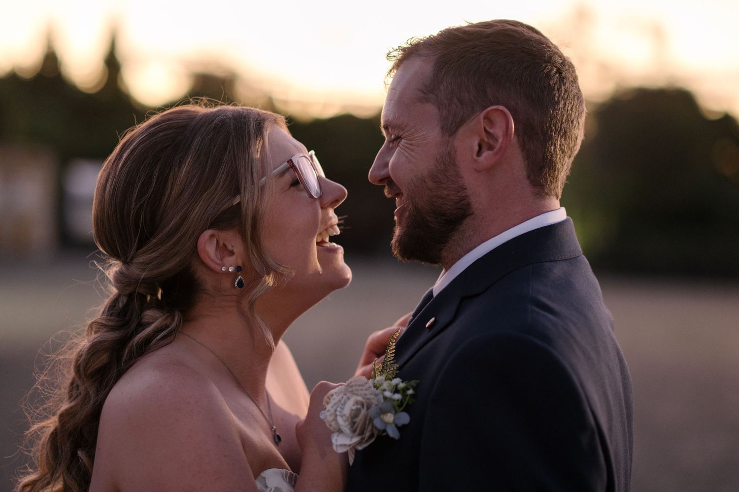 Couple shares joyful laughter during outdoor sunset Vilagrad Winery wedding photo session with warm backlight.