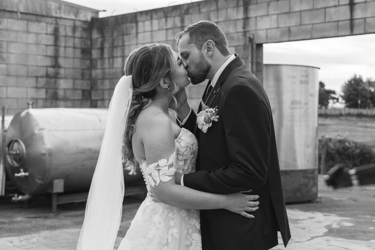 Black and white romantic wedding photo shows a tender moment between newlyweds sharing an intimate embrace at Vilagrad Winery.