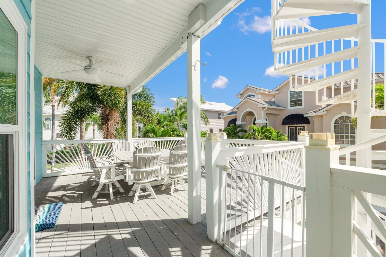 Panoramic view of a spacious white balcony with outdoor seating against a bright blue sky.