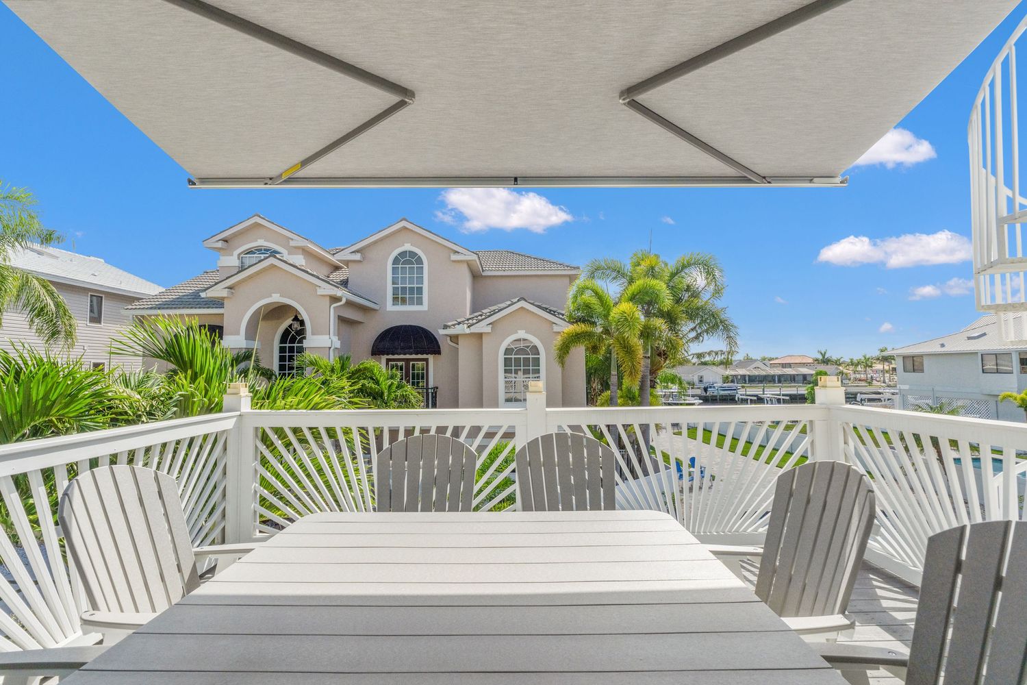 Expansive white balcony with Adirondack chairs offering views of Mediterranean-style architecture.