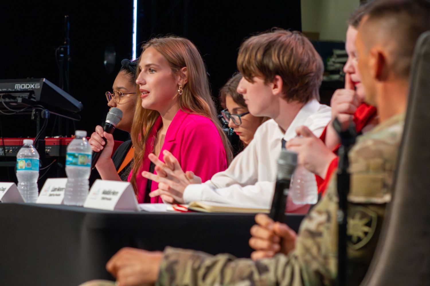 Group seated at conference tables in a dimly lit room during a presentation.