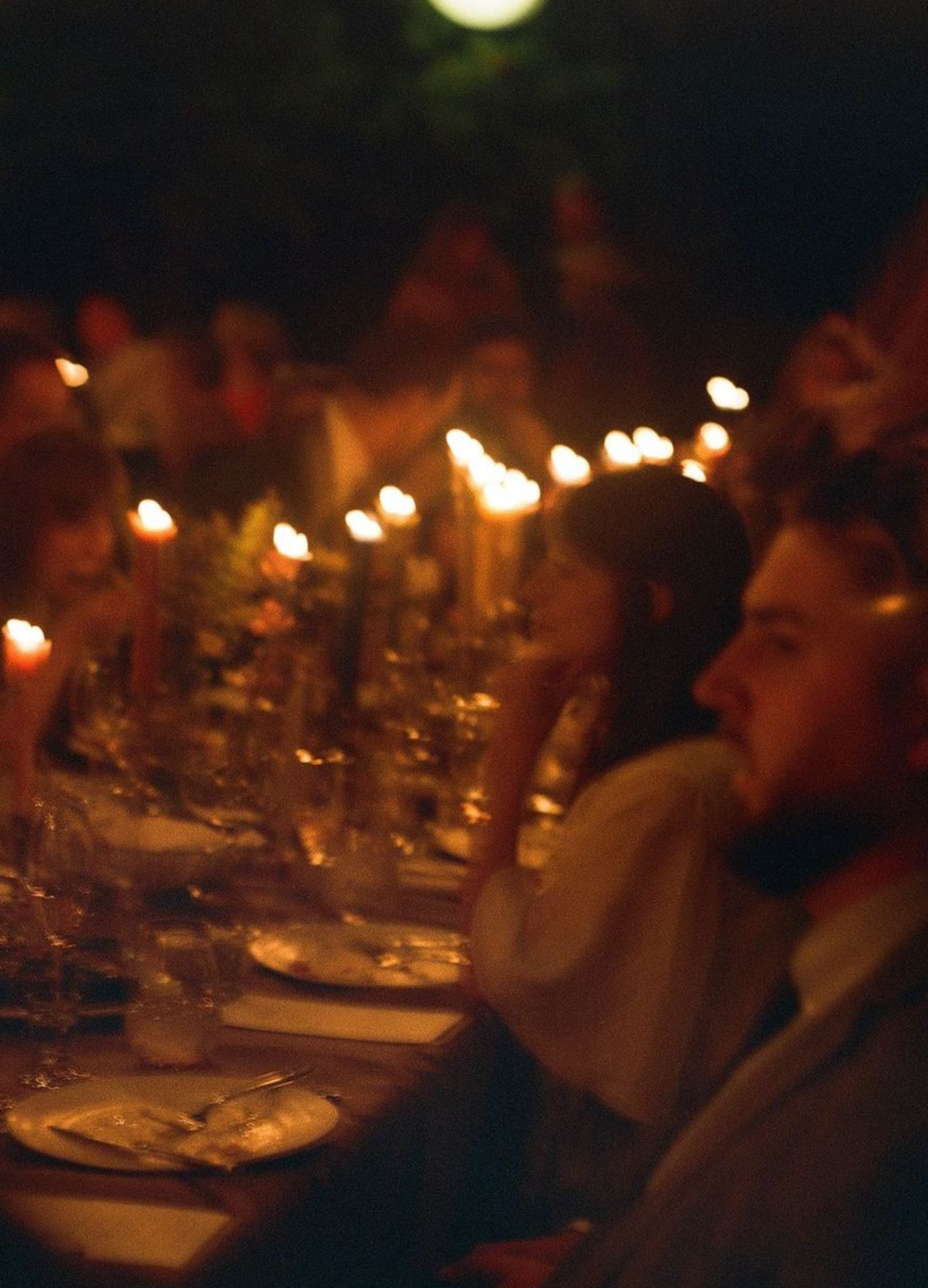 Candlelit reception dinner table with bokeh lights creating an intimate atmosphere.