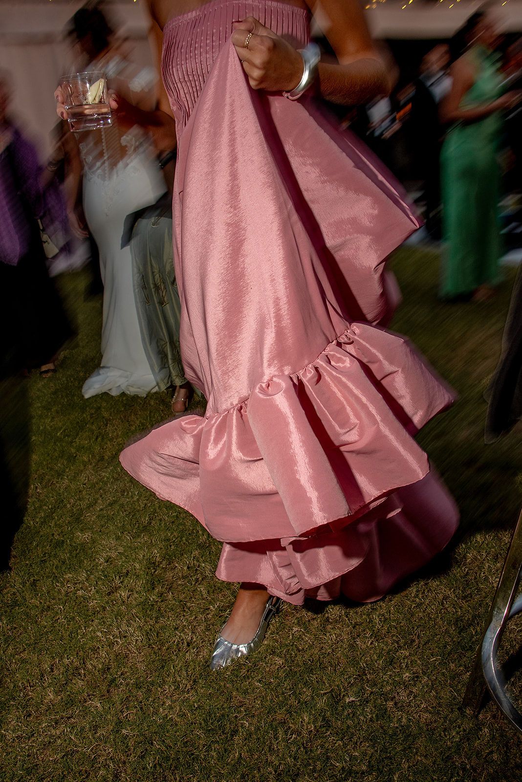 A pink formal dress twirls on a dance floor, capturing the flowing movement of its ruffled fabric during a celebration.