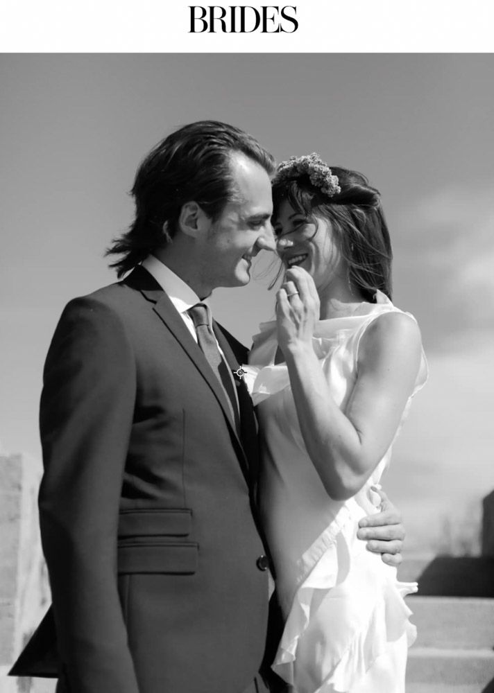 Black and white photo of a bride and groom sharing a tender moment, featured in Brides magazine.
