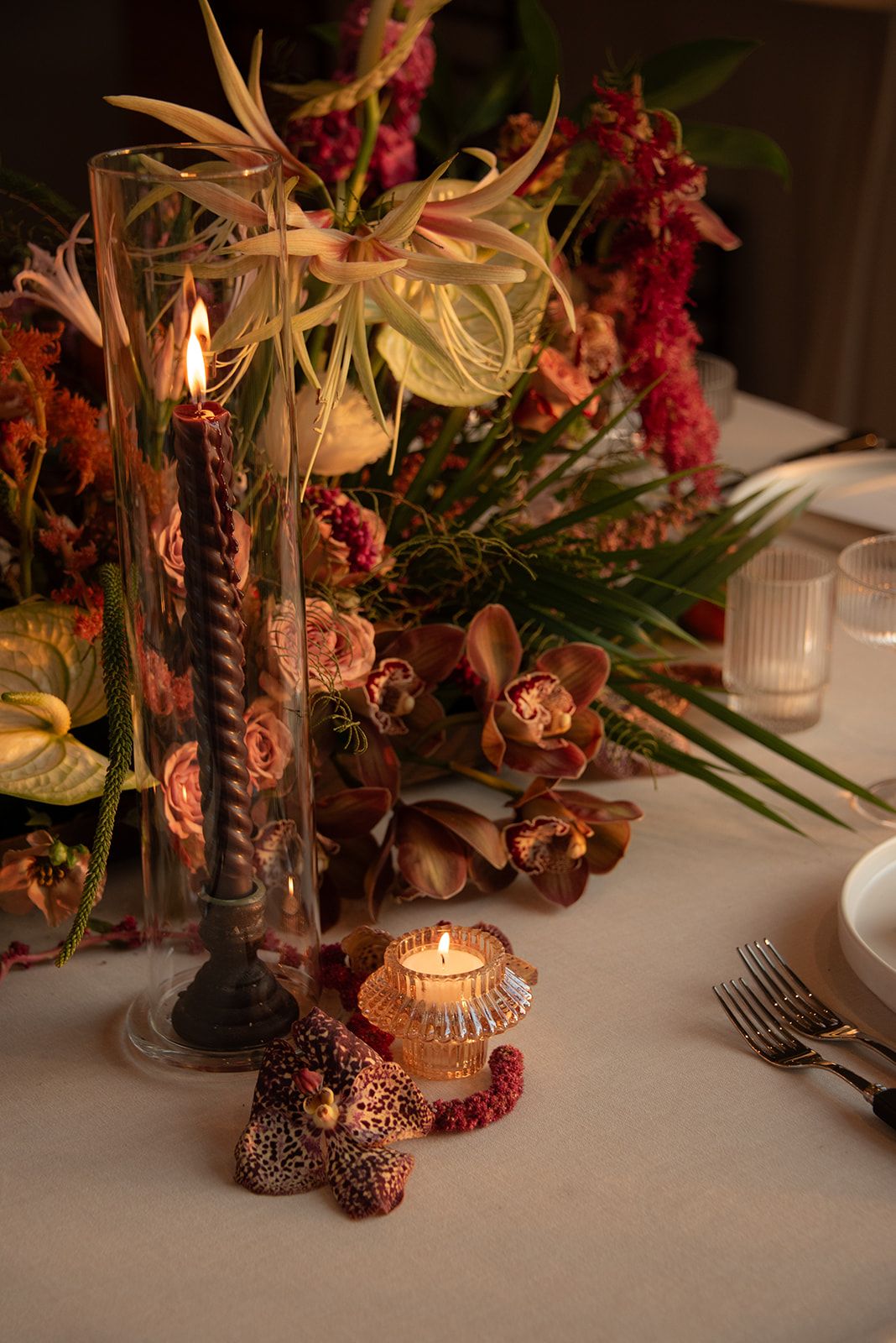 Elegant table setting with moody floral arrangements and glowing candles creating a romantic autumn ambiance.