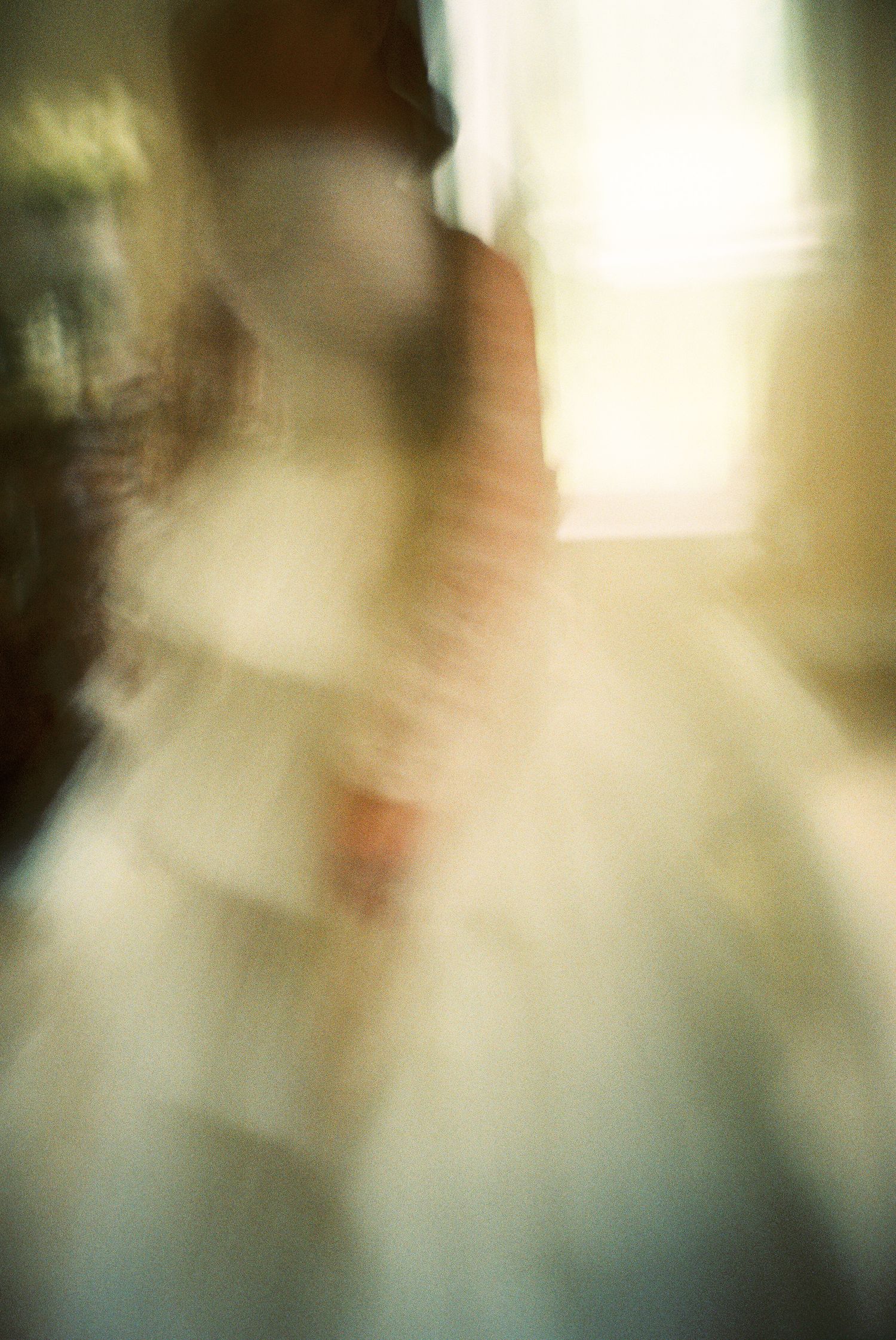Blurred artistic photograph showing a soft ethereal silhouette against a warm glowing background.