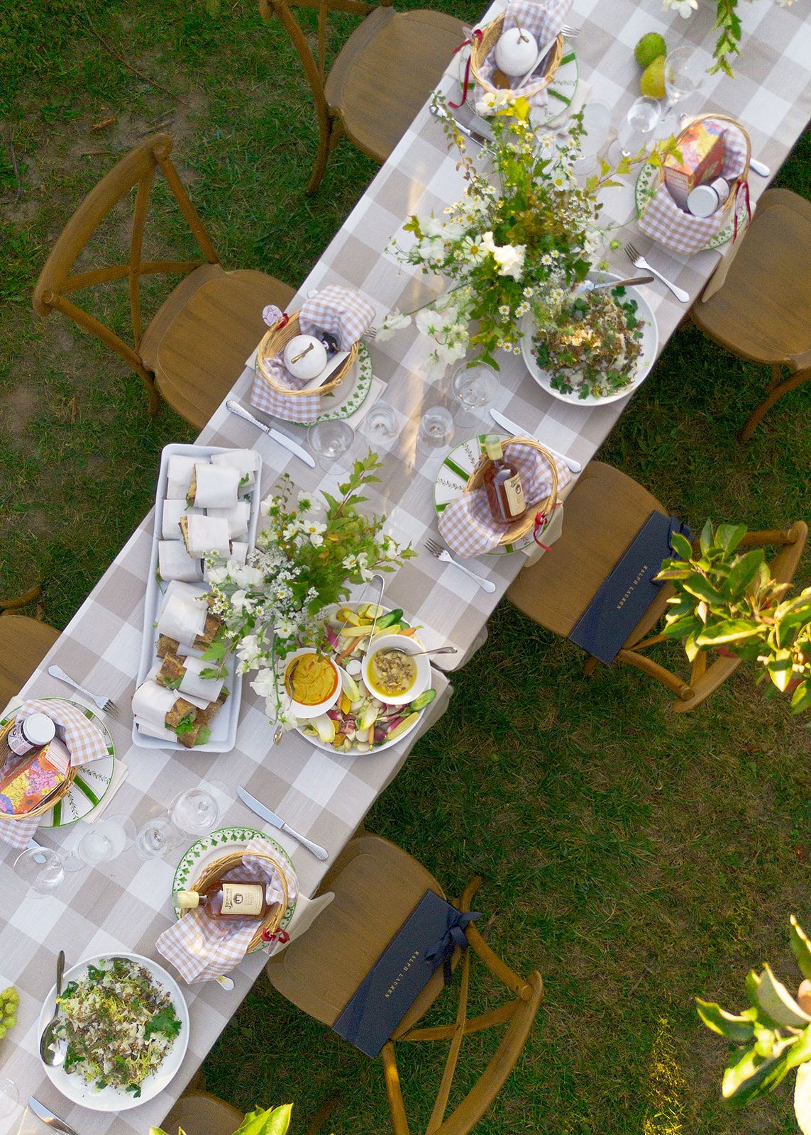 Rustic outdoor table setting with gingham tablecloth, wildflower centerpieces, and wooden chairs for garden dining.