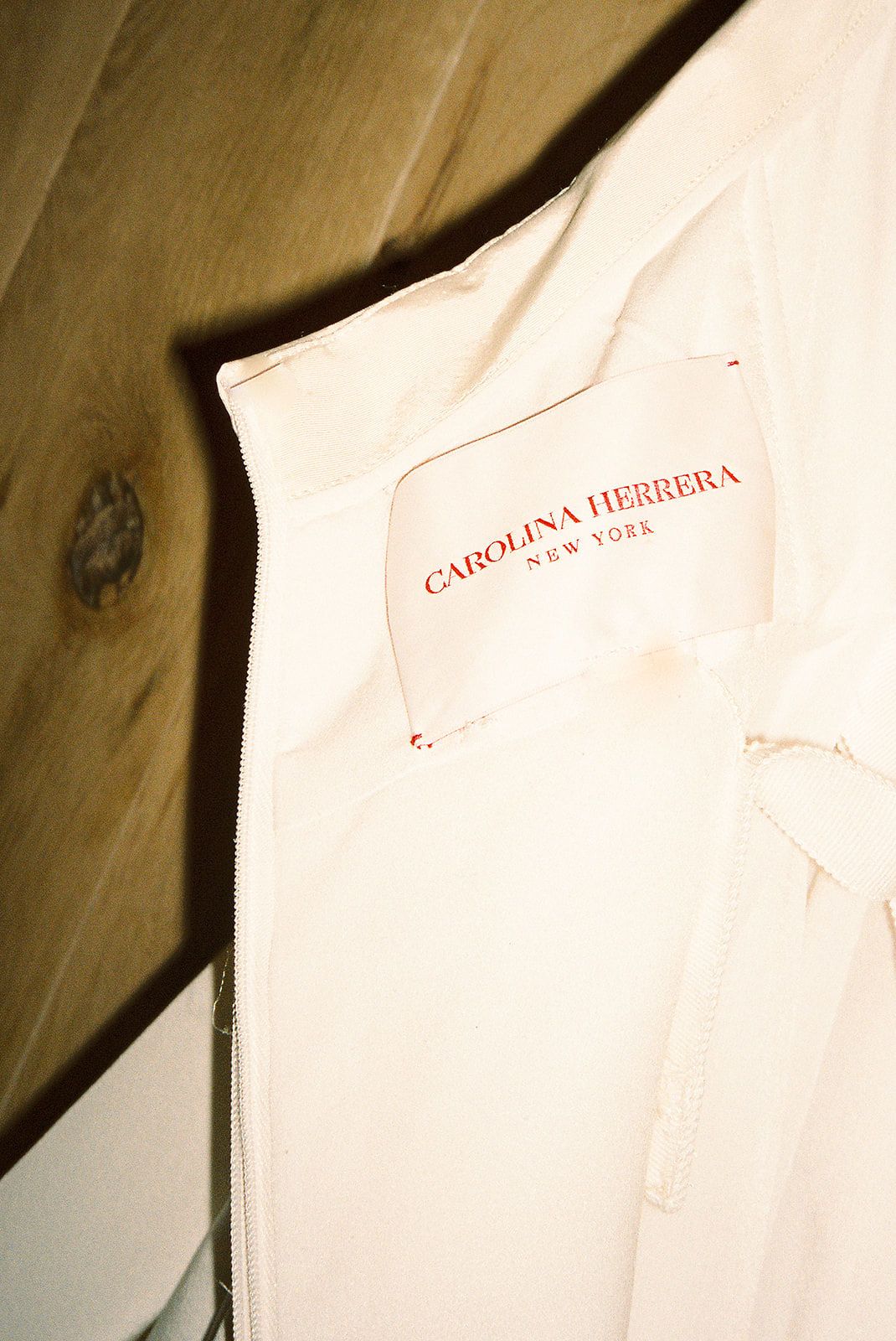 White dress shirts hanging on wooden hangers against a light colored wall.