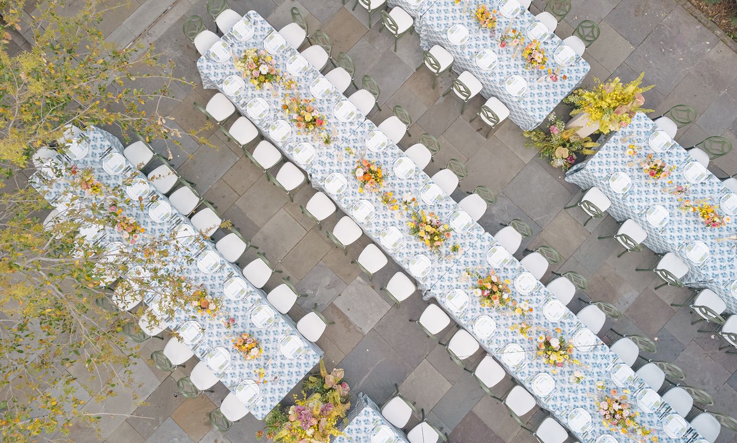 Aerial view of white beach chairs arranged in neat rows along a sandy shoreline with scattered autumn leaves.