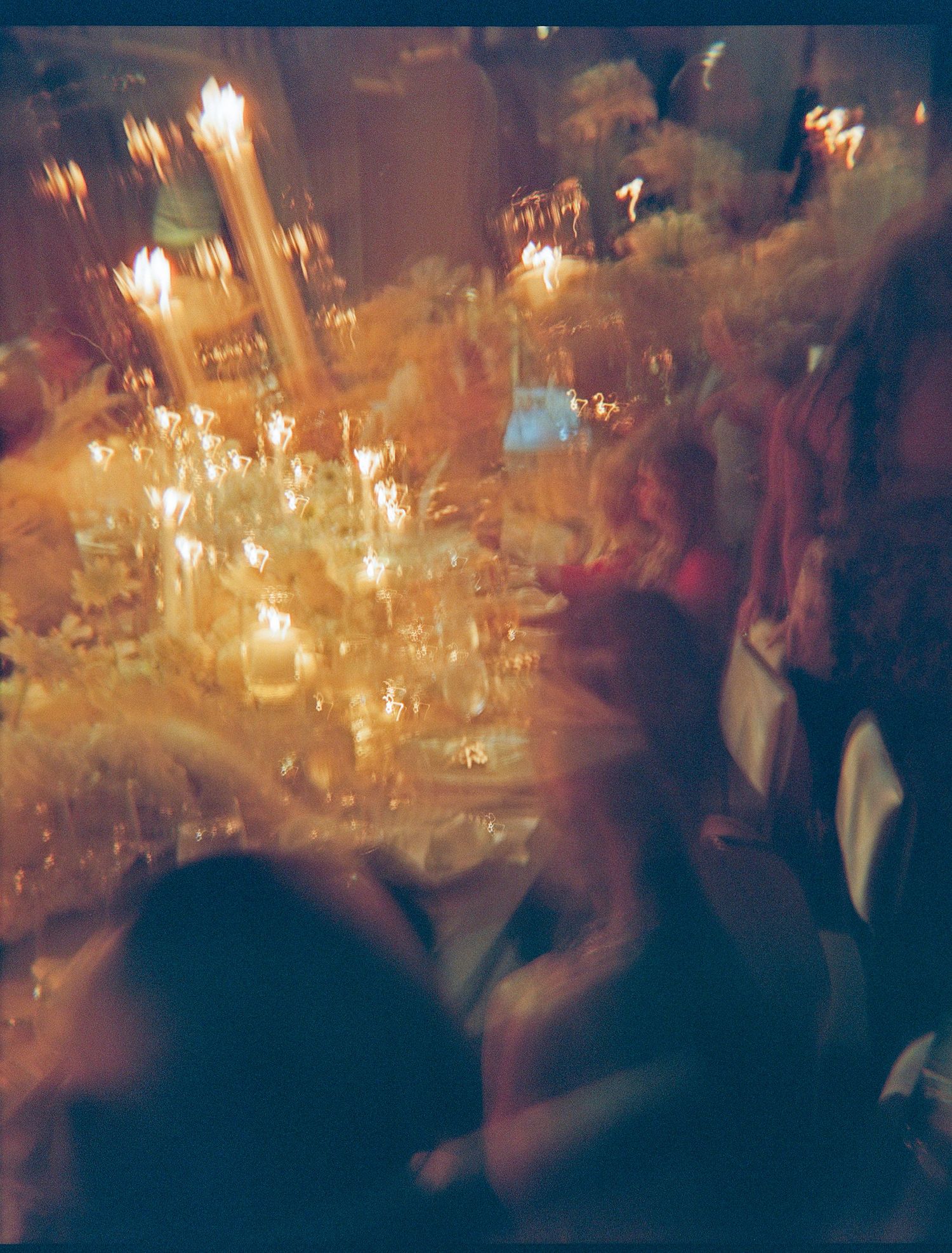 Blurred motion of people dancing and celebrating at an evening party with warm glowing candlelight illuminating the scene.