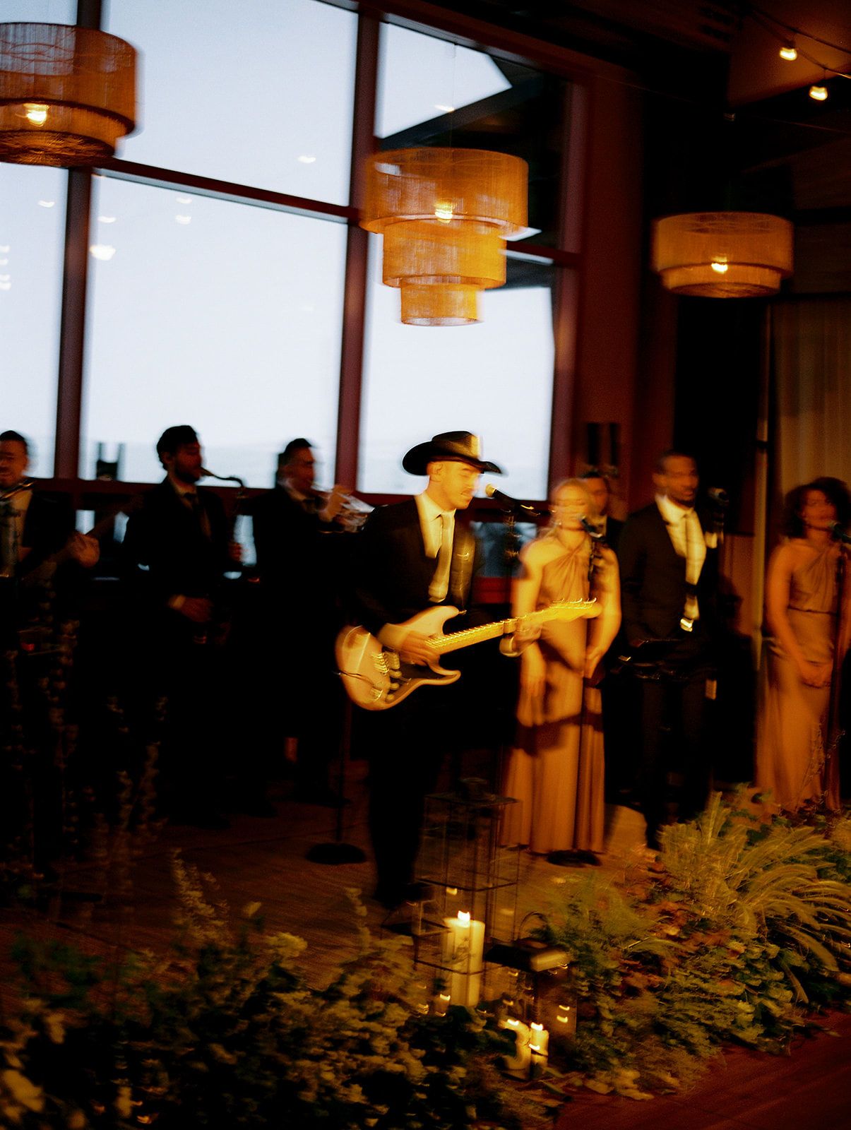 A series of connected images showing a wedding ceremony in a dimly lit venue with warm lighting and floral decorations.