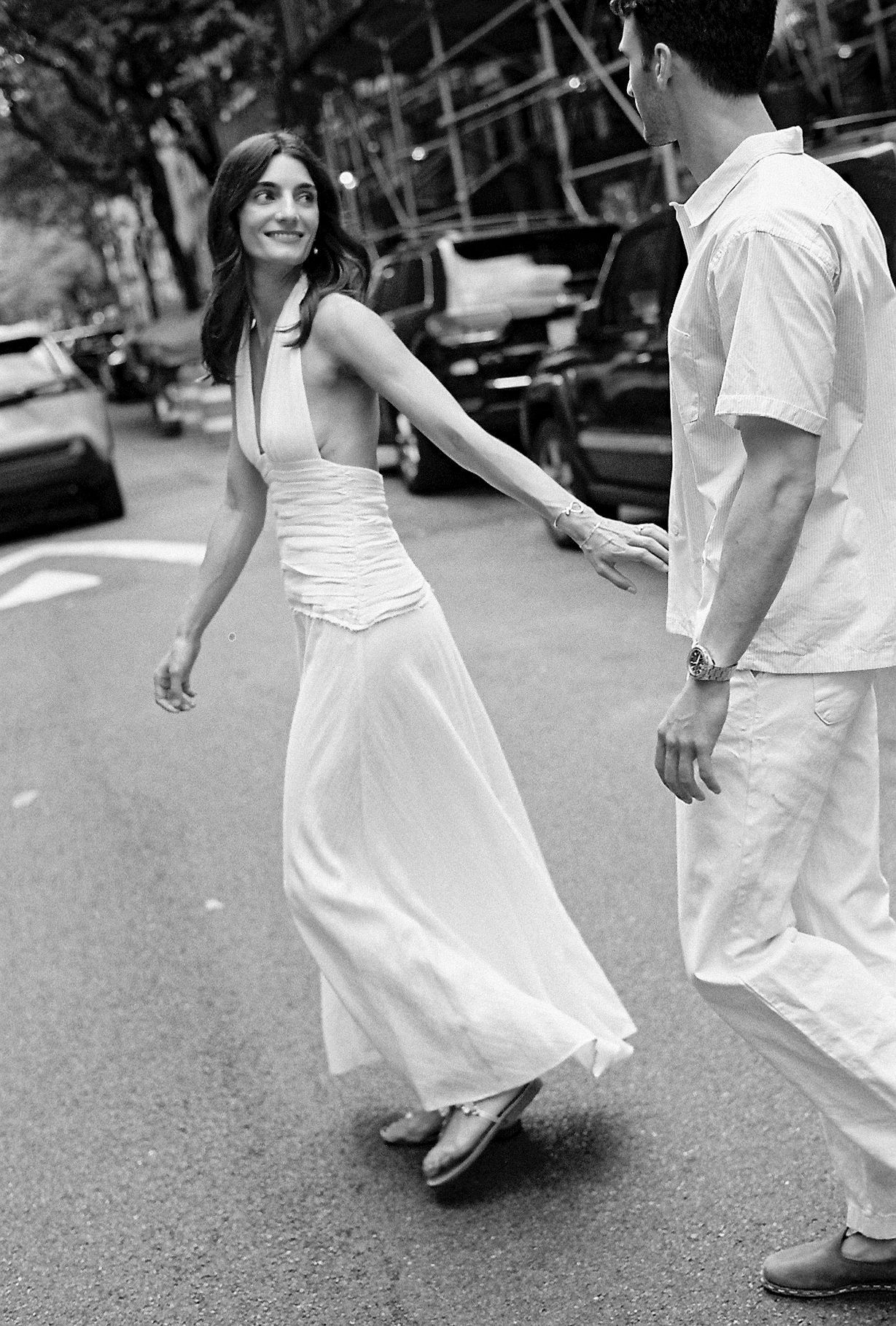 Black and white sequence of a couple in white clothing dancing together on a city street.