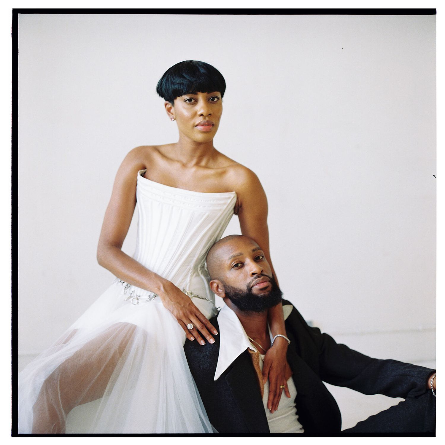 Two figures in contrasting black and white outfits posed together in an artistic photoshoot.