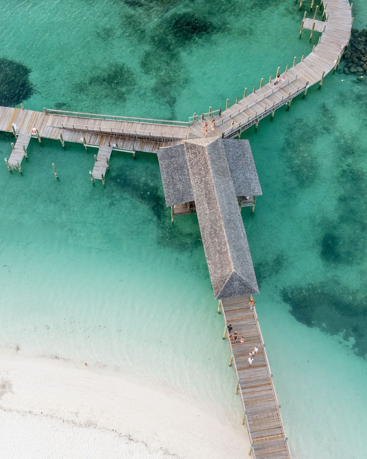 Aerial view of wooden boardwalks extending over crystal clear turquoise waters in a tropical paradise.