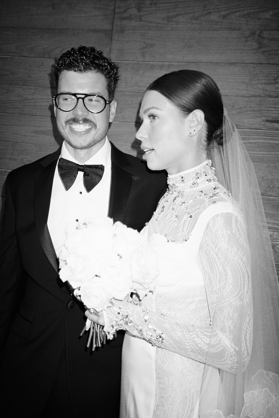 Black and white portrait of a wedding couple with bride holding white floral bouquet.
