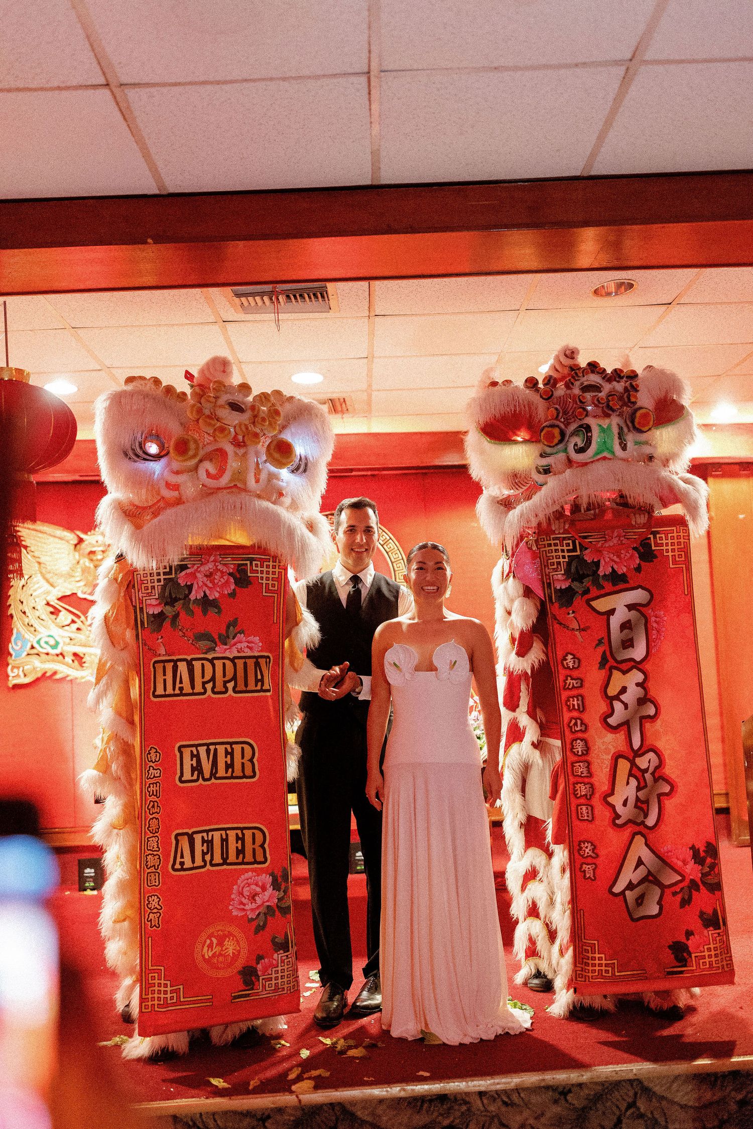 Wedding reception decor features red-lit walls with artistic panels and silhouettes creating a romantic ambiance.
