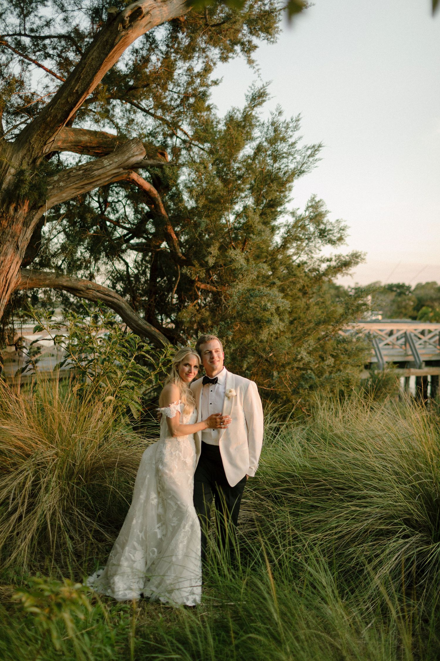 Couple enjoying a romantic moment among tall grass and trees at sunset.