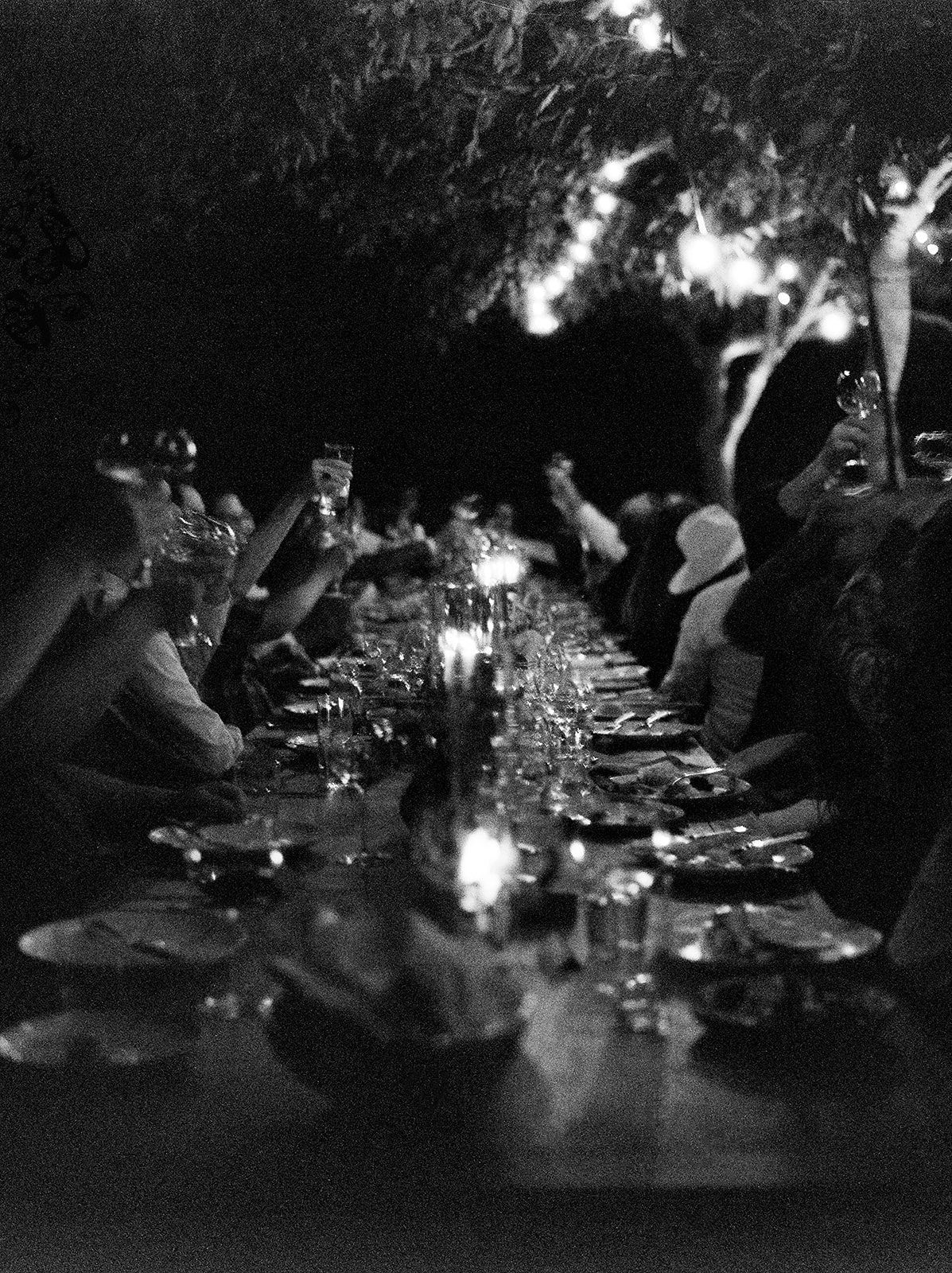Candlelit dinner tables set up outdoors at night with glowing ambient lighting.