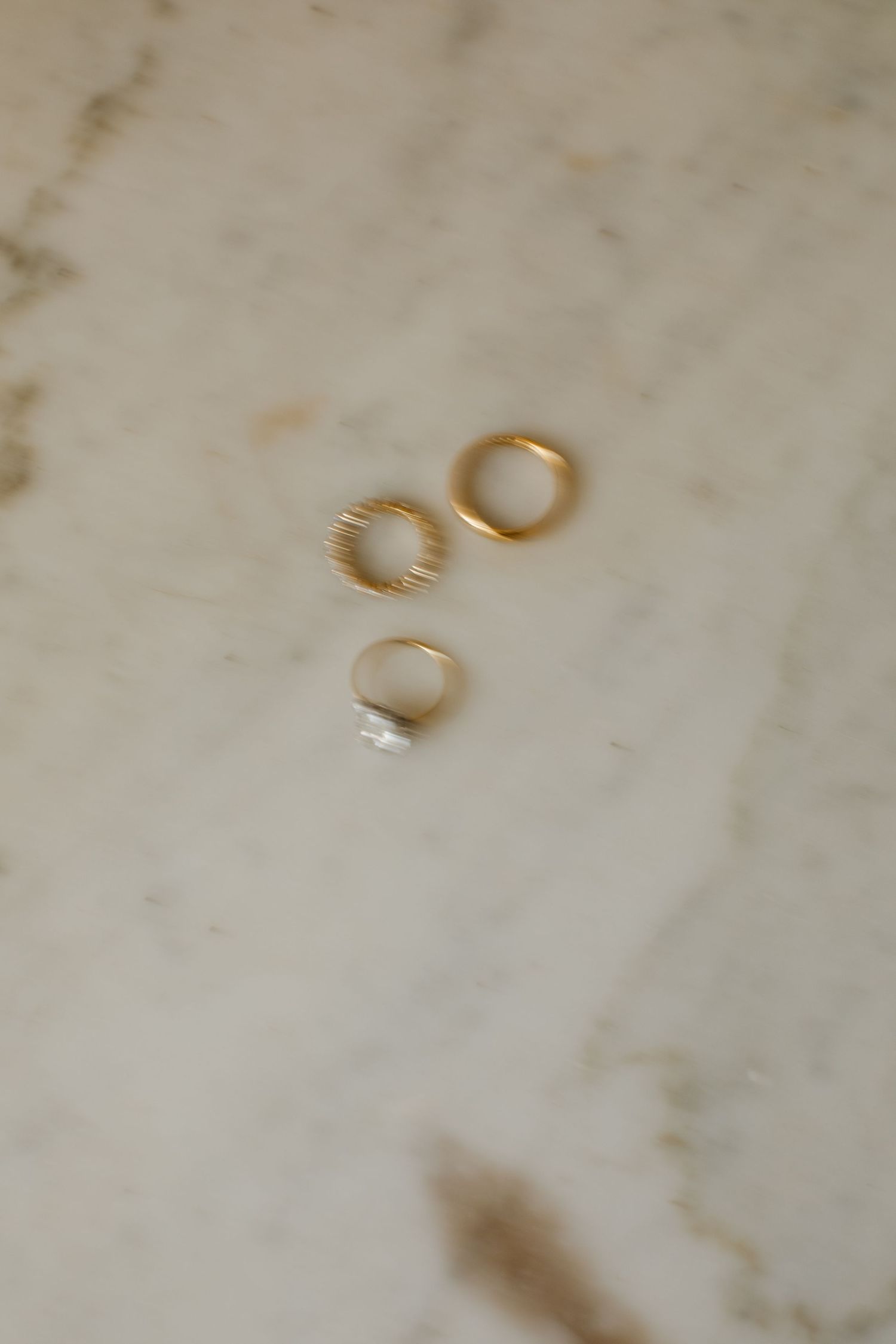 Wedding rings casting shadows on a textured white surface.