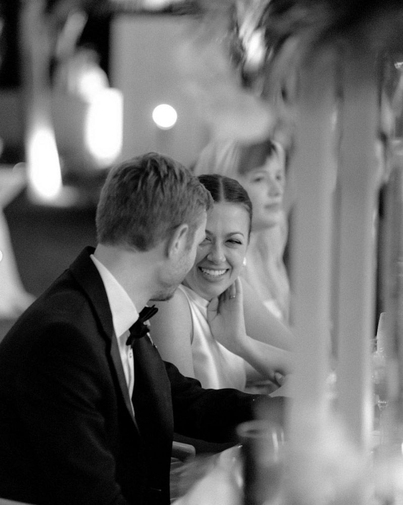Black and white photo of a smiling bride and groom in formal attire at their wedding reception.