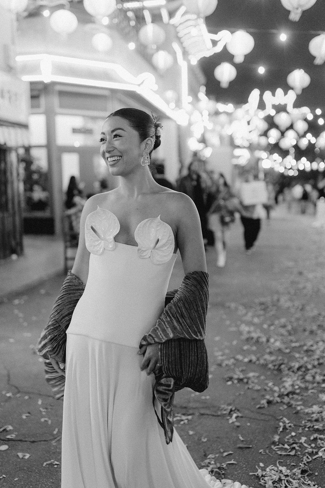 Black and white sequence of a bride in a white dress posing under illuminated lanterns at night.