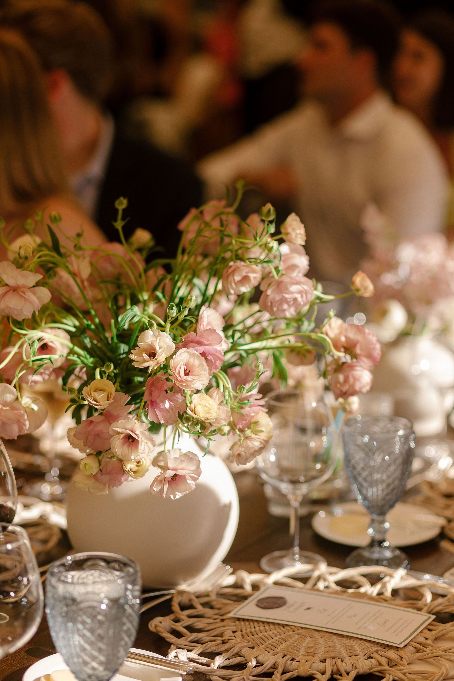 Elegant table setting with pink floral centerpieces and crystal glassware at a formal wedding reception.