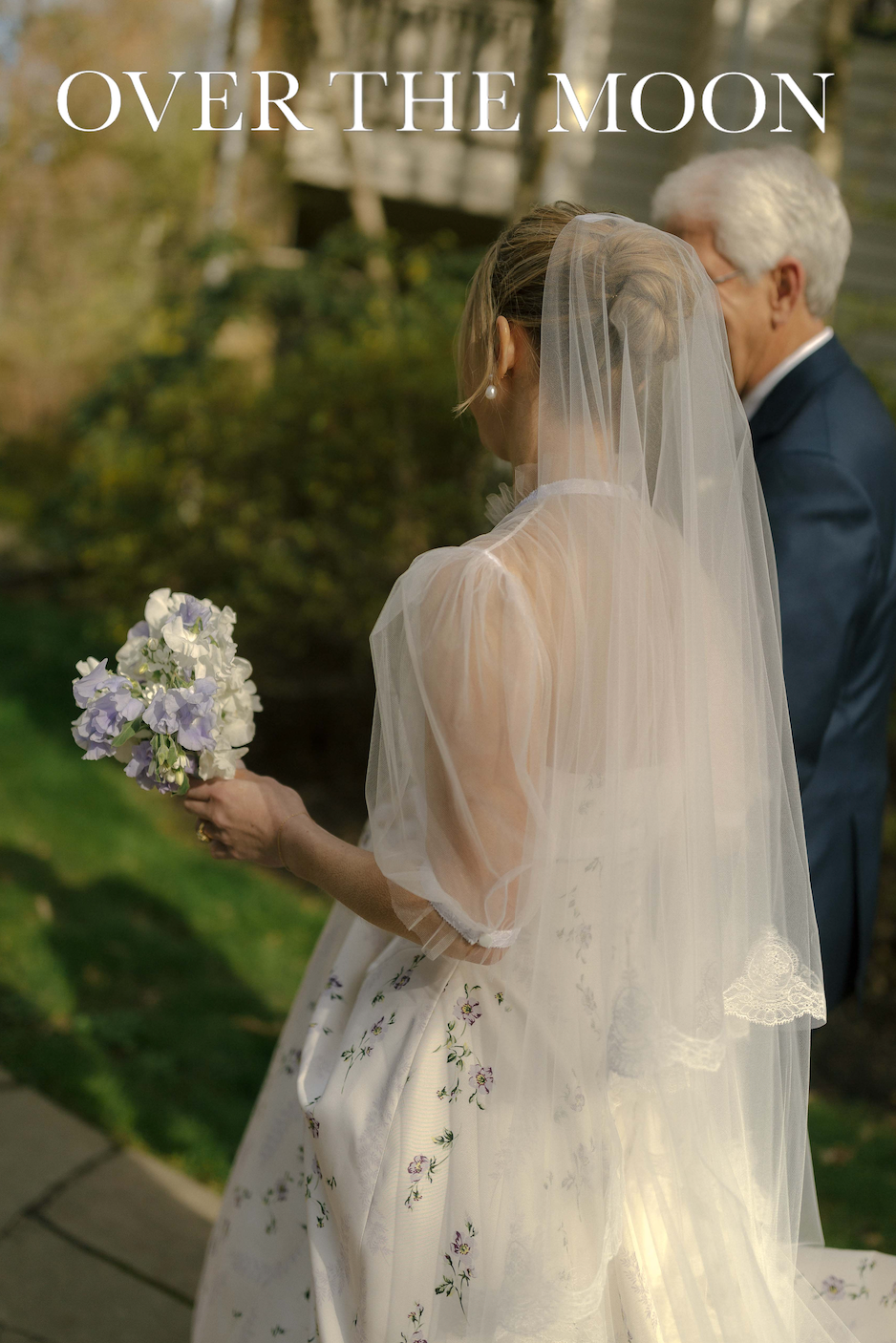 Over The Moon wedding photo of bride holding purple bouquet in embellished gown with veil.