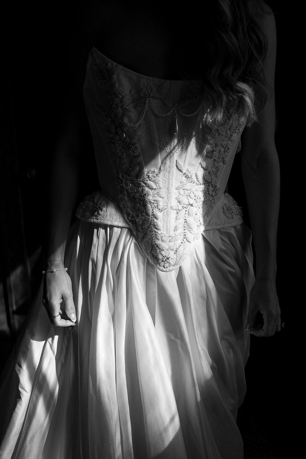 Black and white artistic photo series showing details of a white lace wedding dress with flowing fabric in dramatic lighting.